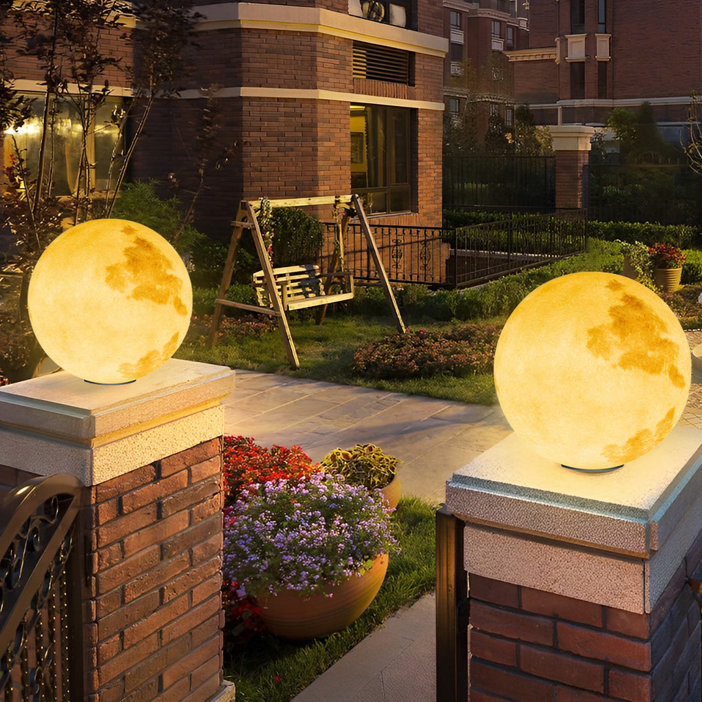 Moon-shaped stone pillar light on stone pedestal beside outdoor seating area.