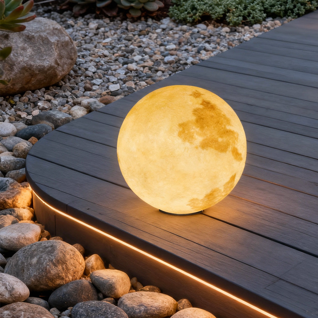Moon-shaped stone pillar light casting soft light on wooden deck with pebble garden.