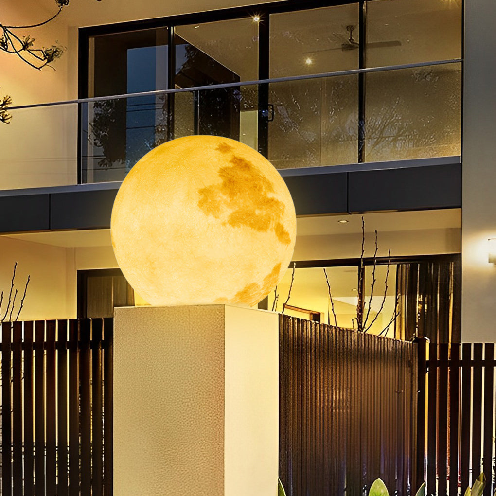 Moon-shaped stone pillar light casting warm glow on wooden deck at dusk.