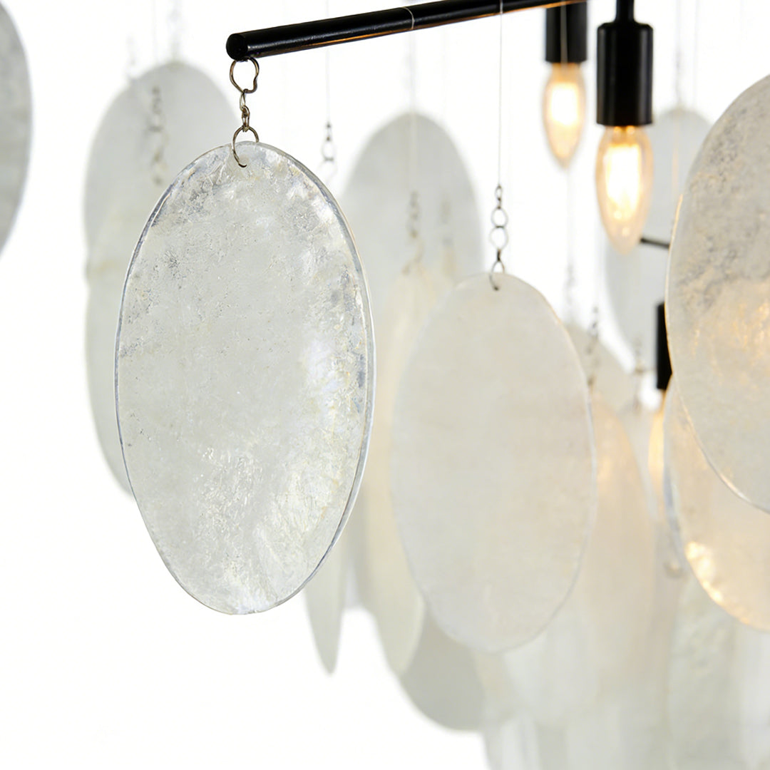 Mother of pearl chandelier detail showing translucent shell pieces hanging from a metal frame with soft ambient illumination