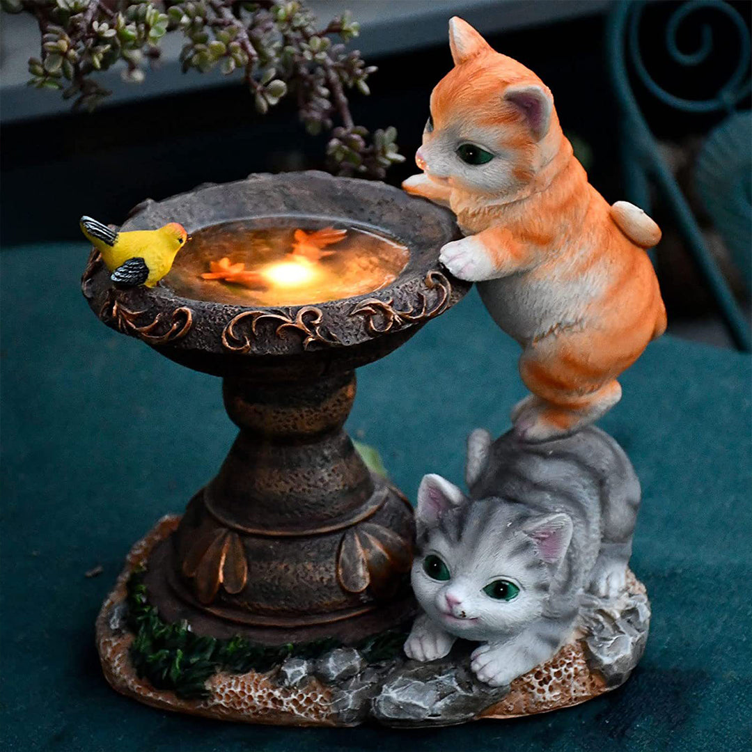 Multi-kitten fountain display with orange tabby and gray cats around lit water feature