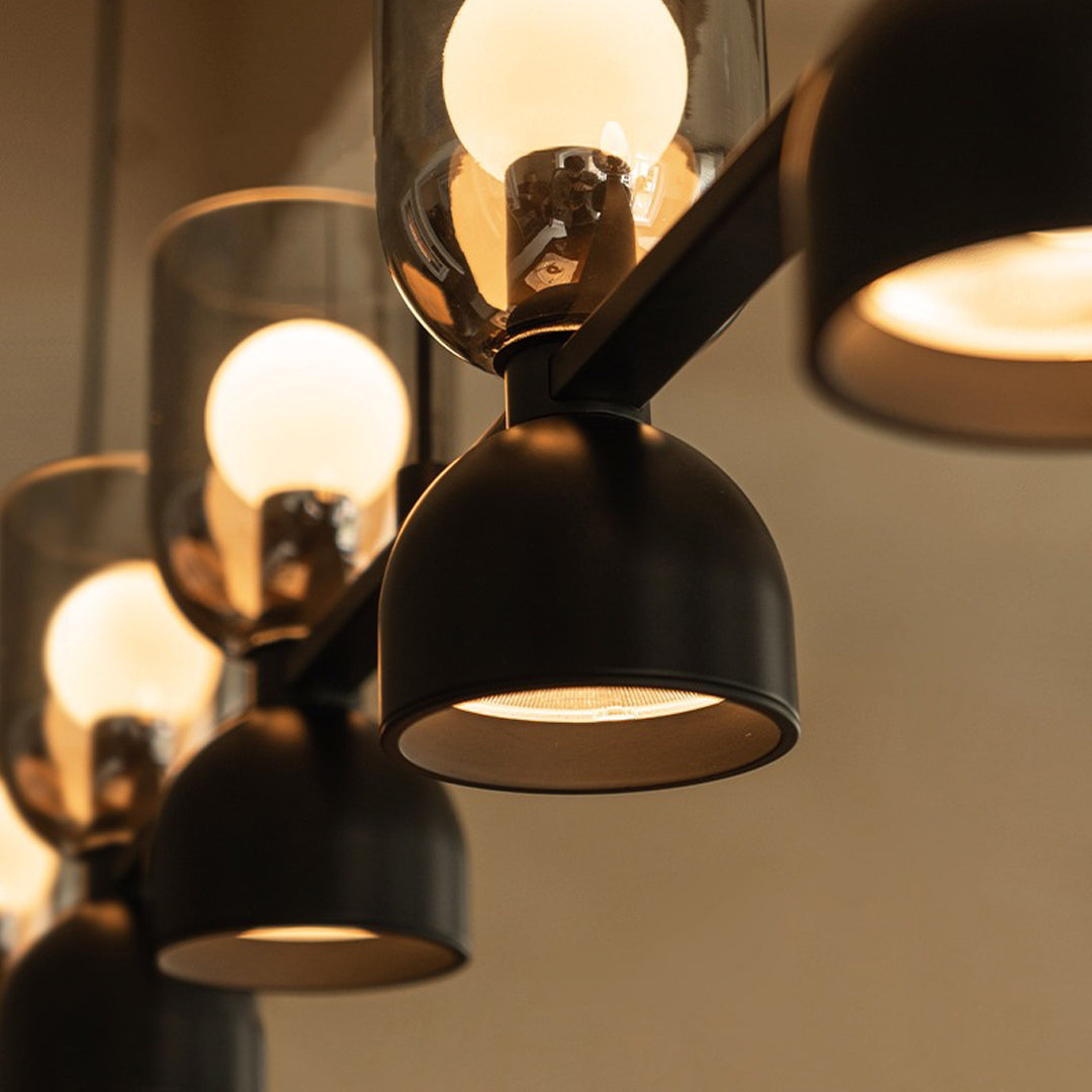 Detailed close-up of multi-light glass pendant chandelier with warm illumination and matte black finish.