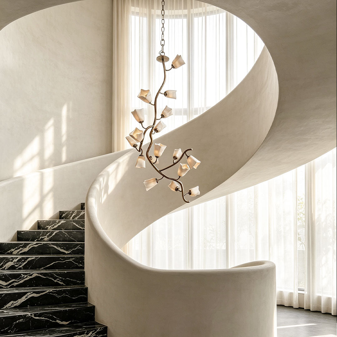 Multi light pendant chandelier suspended above a sweeping staircase in a bright contemporary foyer.