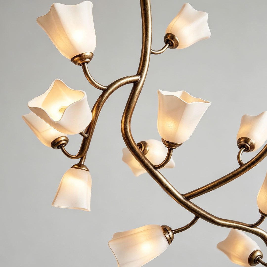 Close-up of a multi light pendant chandelier showing branching metal arms and soft frosted flower-shaped shades.