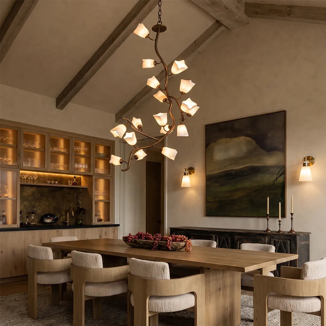 Multi light pendant chandelier hanging above a dining table in a warm rustic dining room with exposed ceiling beams.
