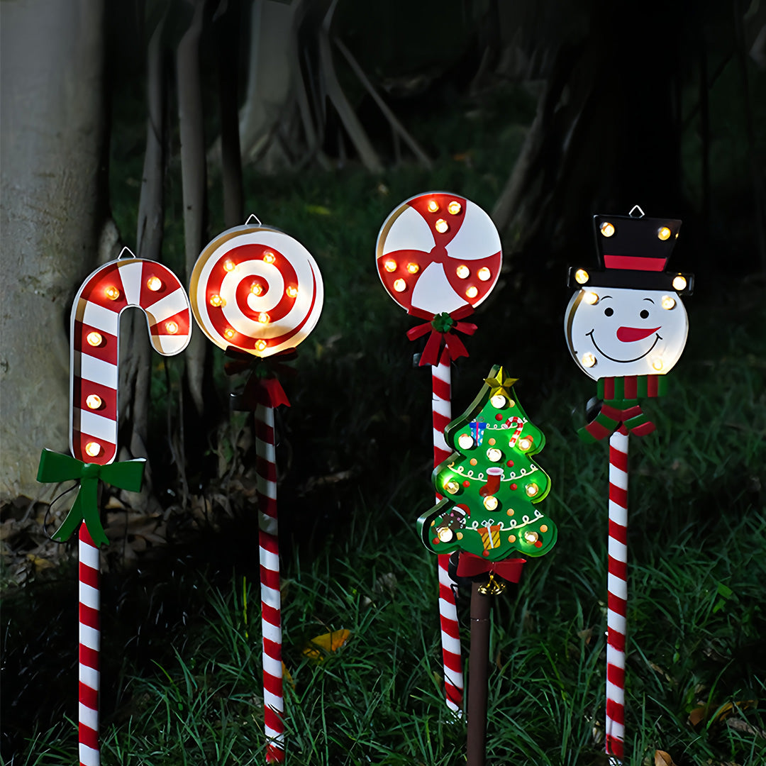Set of multiple glowing ground stakes for Christmas lights in festive shapes displayed outdoors at night.