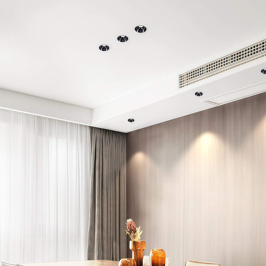 Multiple adjustable downlights illuminating minimalist kitchen with white cabinetry and wood accents