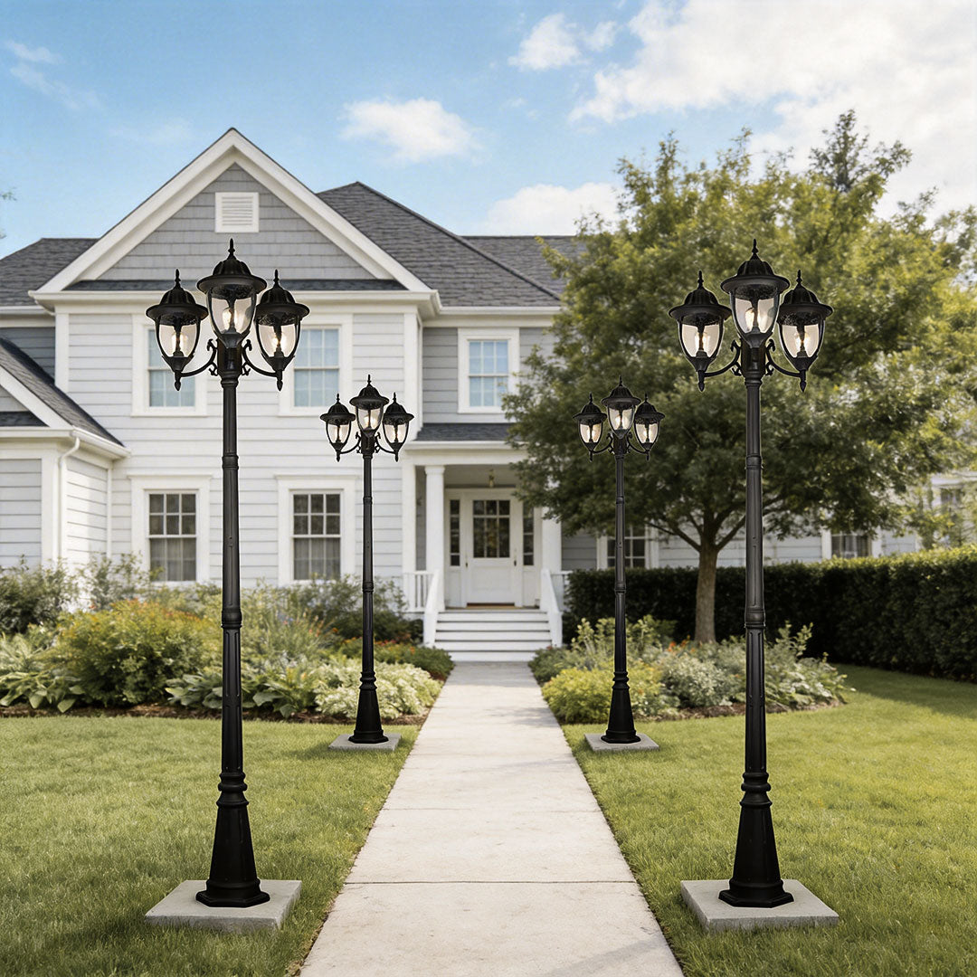 Multiple black street lamp post lights lining a stone walkway to a traditional white home.