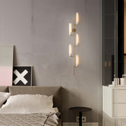 Multiple brass wall lights with glass shades creating layered illumination in contemporary grey bedroom.