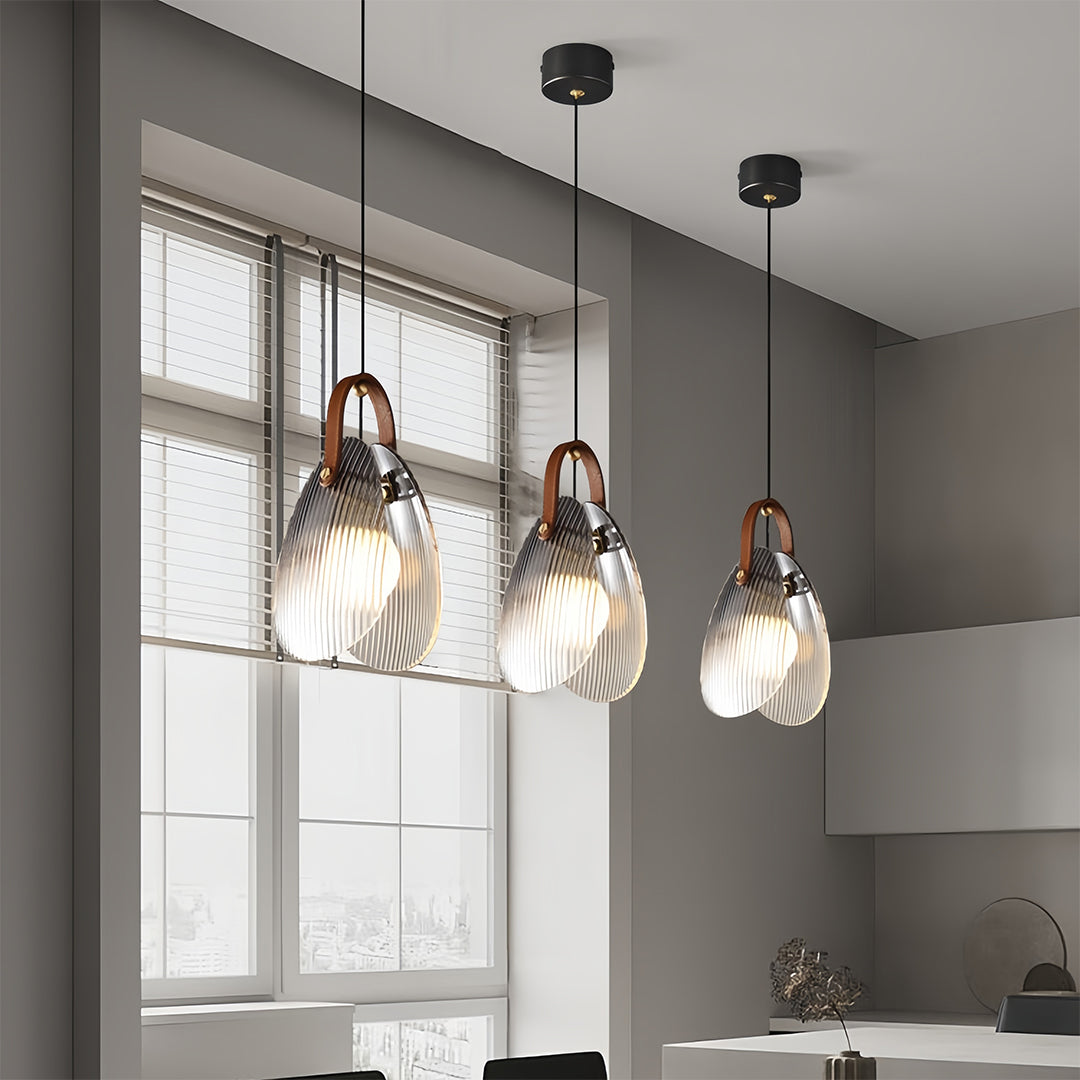 Multiple hanging glass pendant lights suspended at varying heights in modern kitchen space