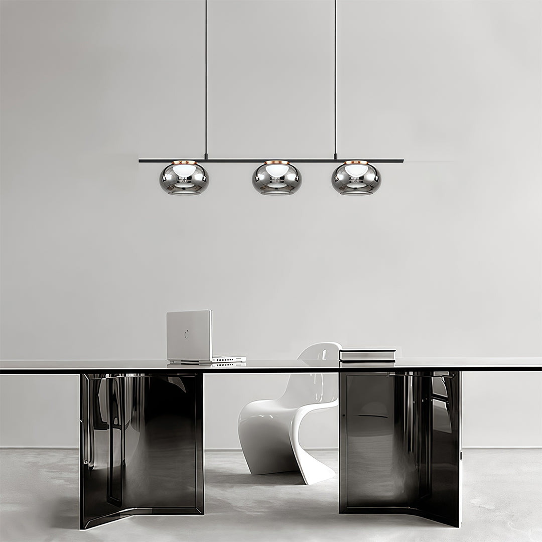 Multiple gray glass pendant lights creating ambient lighting in modern kitchen with black and white cabinetry.