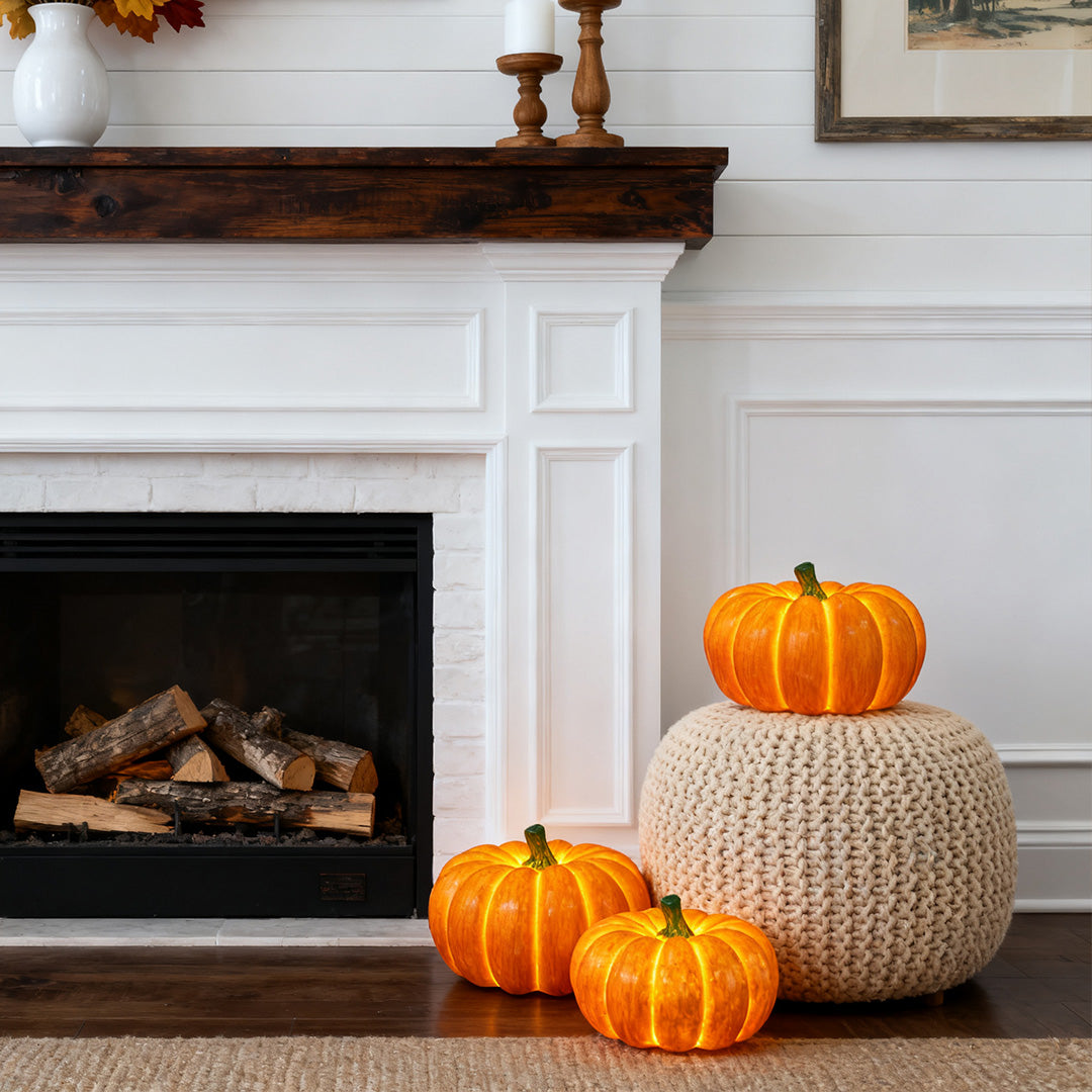 Multiple halloween pumpkin light decorations of various sizes arranged by a cozy white fireplace.