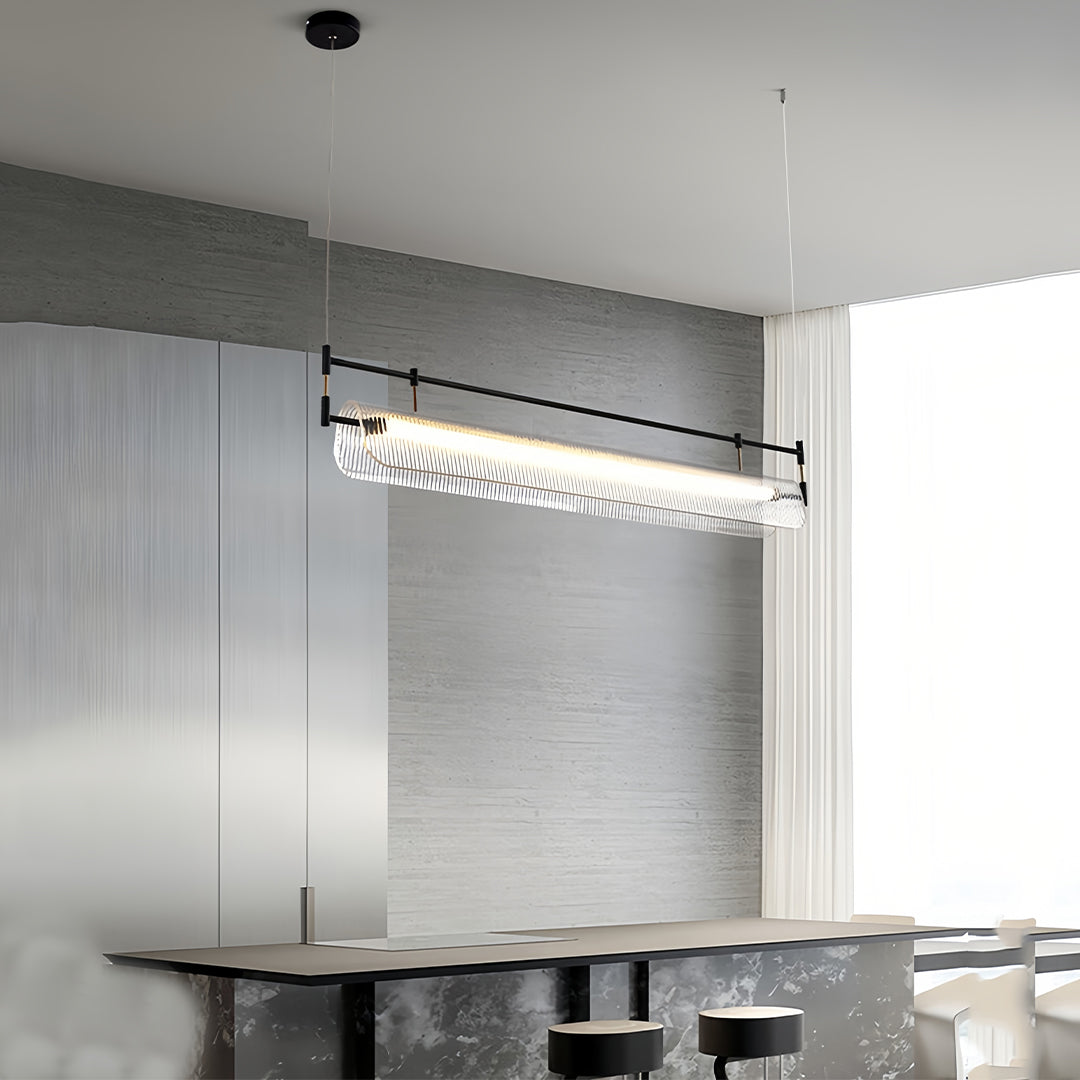 Multiple linear light pendants suspended over modern kitchen island with grey cabinetry.