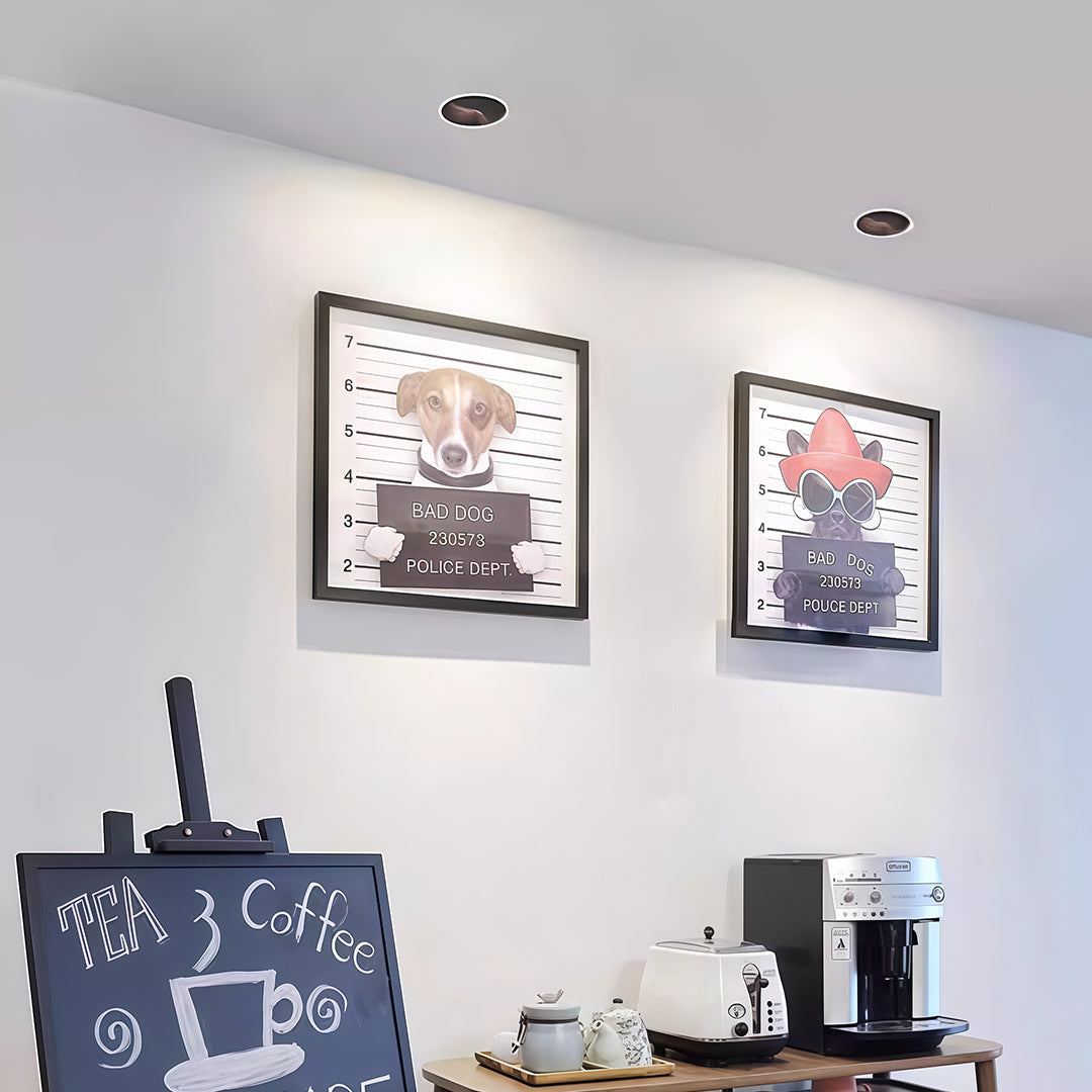 Multiple recessed spotlights brightening modern kitchen with white cabinetry and framed art collection