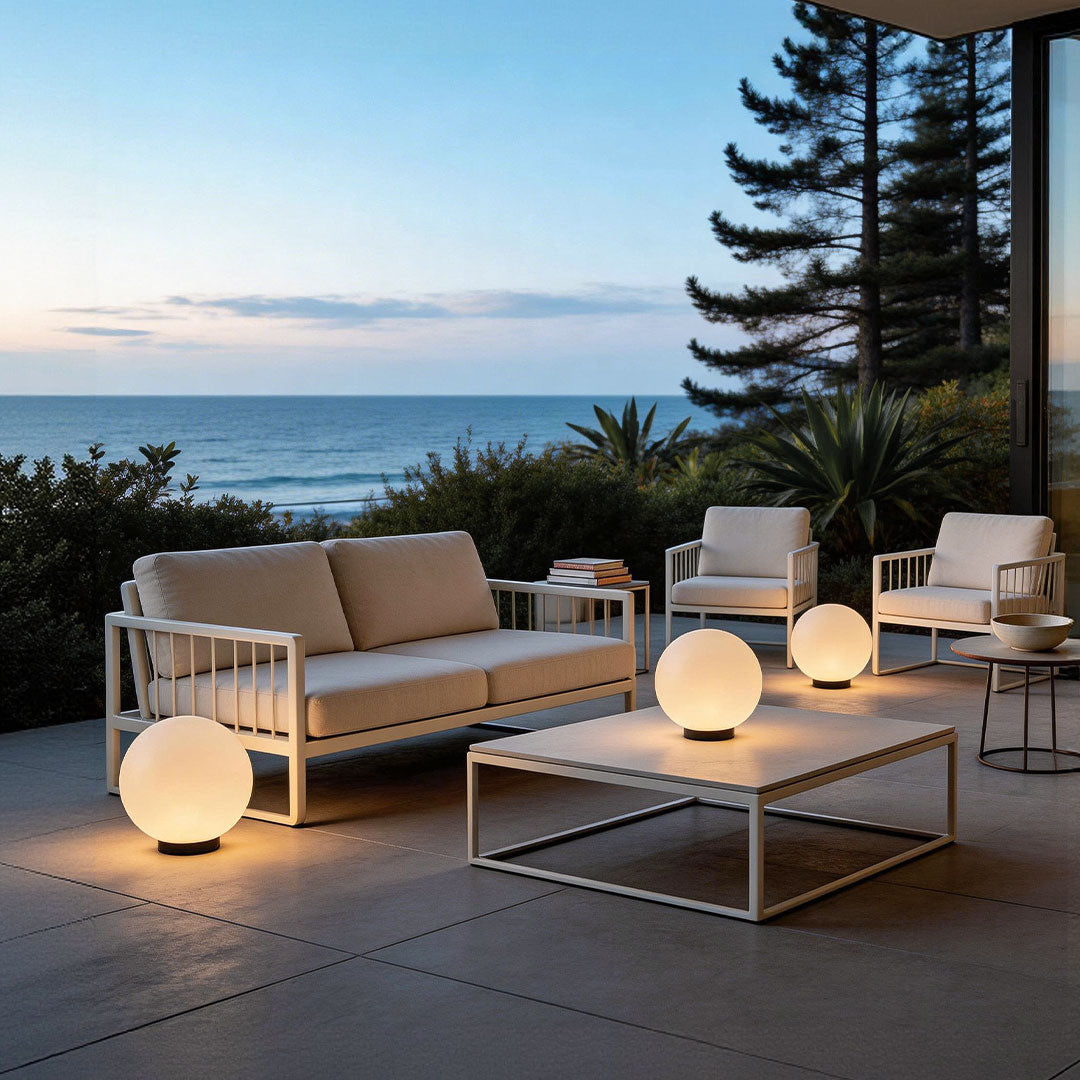 Multiple round landscape lighting globes on a luxury patio with white furniture by the sea!!