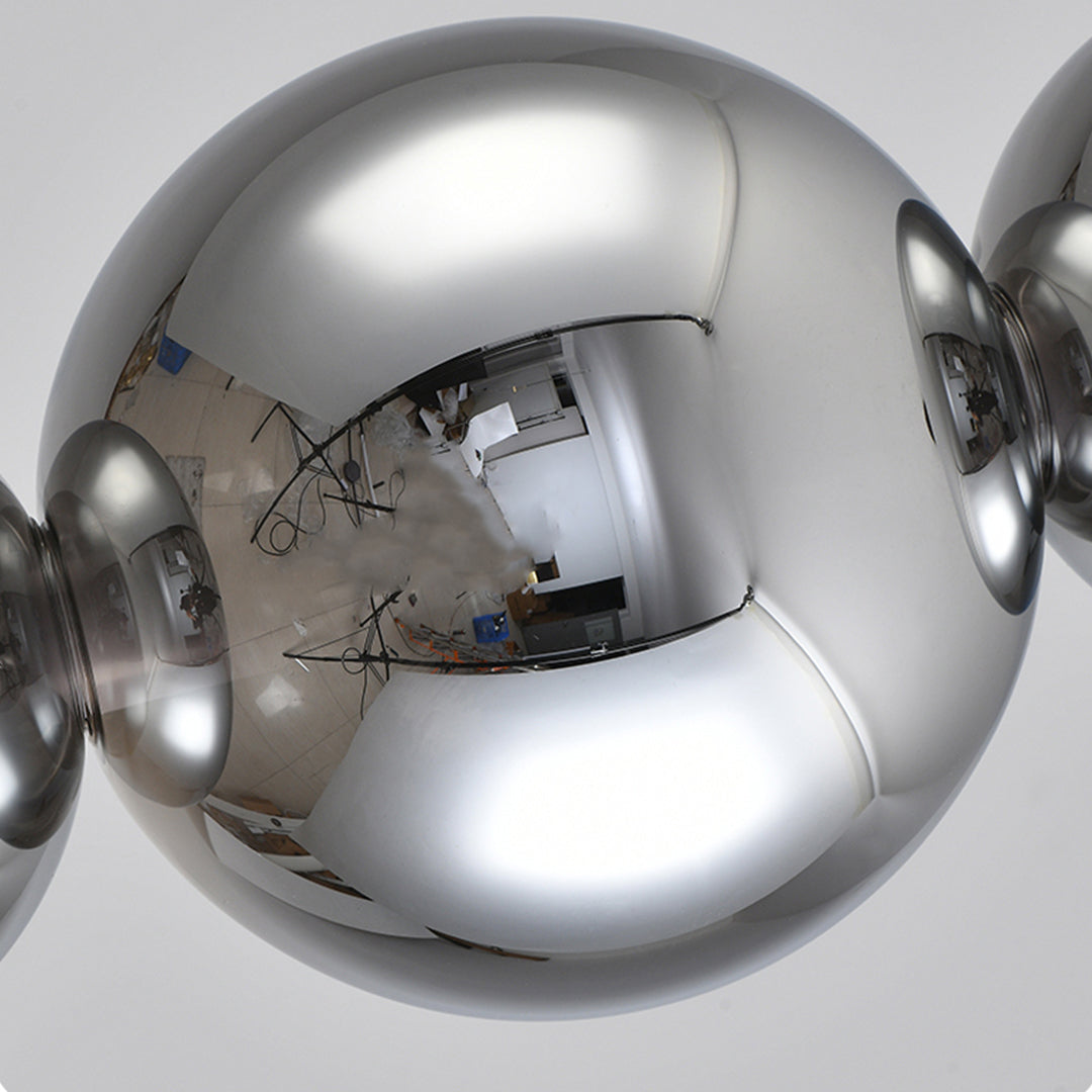 Multiple modern silver pendant light arrangement featuring contemporary clear globes in elegant dining space