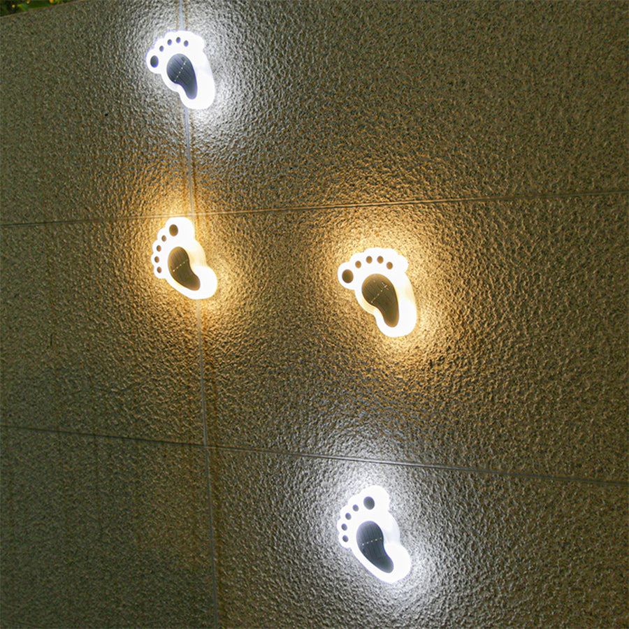 Multiple solar foot lights glowing with warm LED illumination on textured outdoor surface