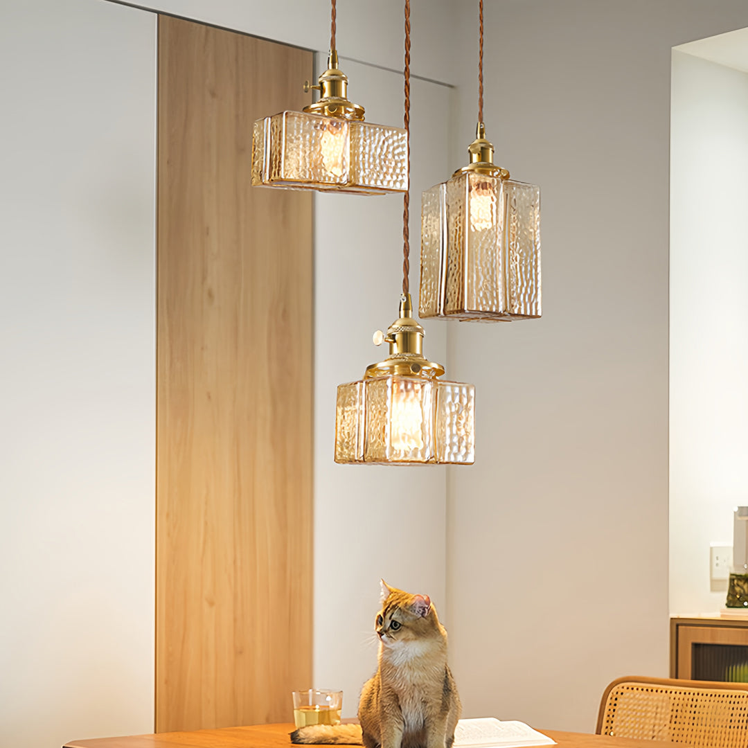 Multiple square glass pendant lights over rustic dining table creating cozy farmhouse atmosphere with natural materials