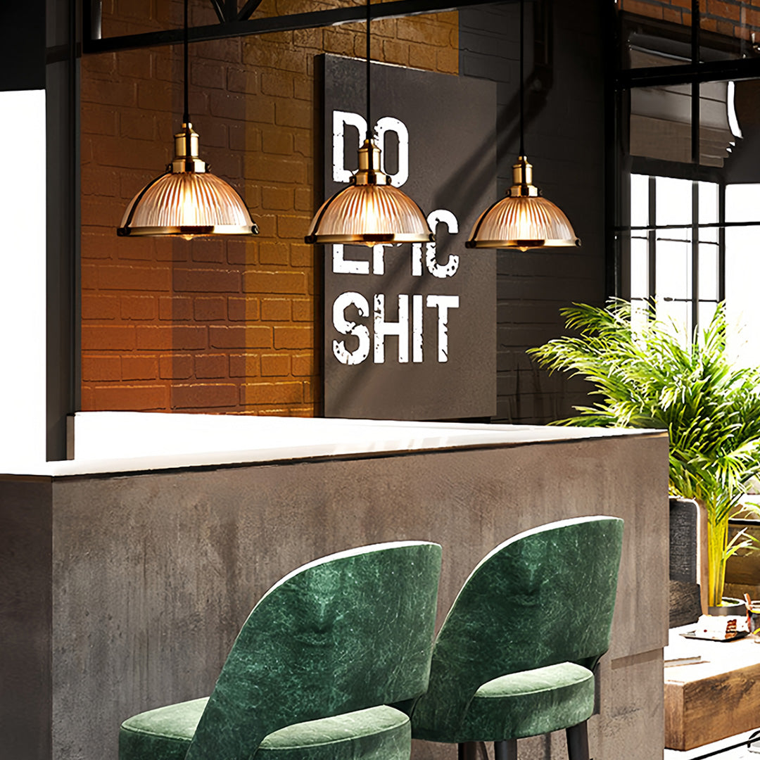 Multiple textured glass pendant lights over kitchen island with brass hardware and warm golden illumination