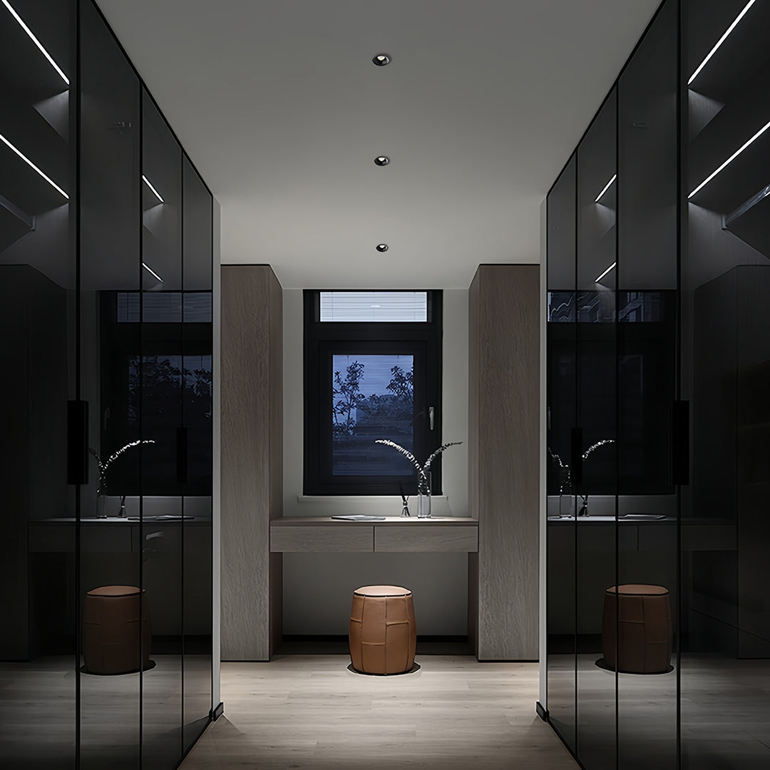 Multiple trimless recessed downlights brightening modern hallway with black cabinetry and marble flooring
