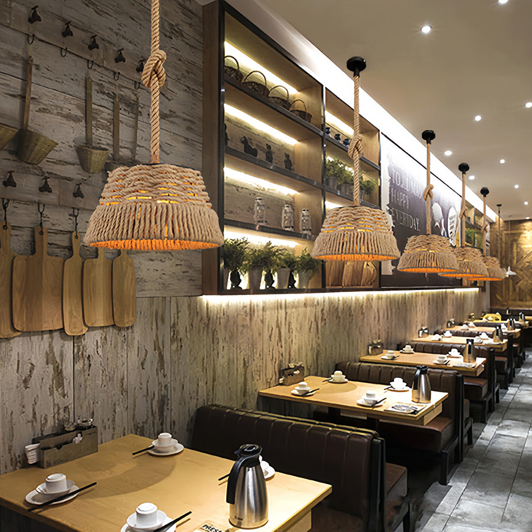 Multiple woven rope pendant lights illuminating a long, rustic commercial dining area with wooden tables and shelving.