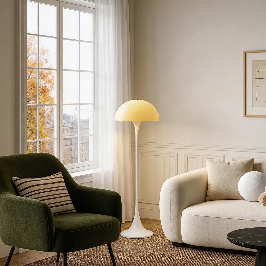 Mushroom floor lamp with a white shade, placed beside an armchair in a bright living room.