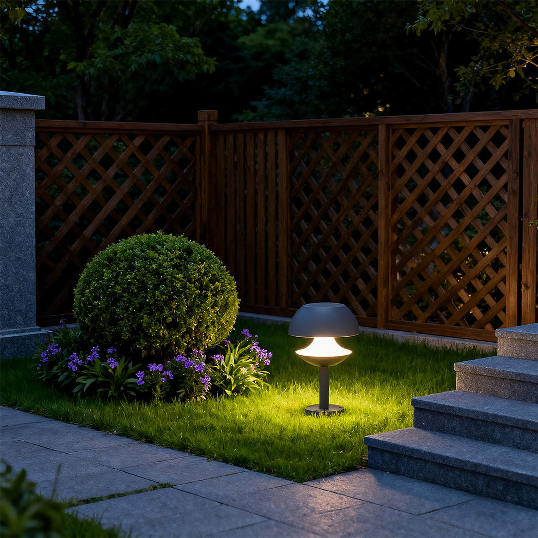 Mushroom path lights brightening garden area near wooden fence with round topiary bushes.