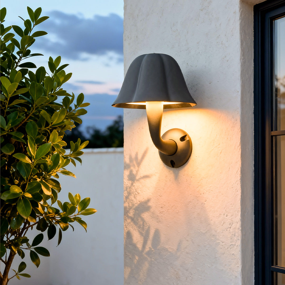Outdoor mushroom wall light illuminating the walkway of a modern house at dusk.