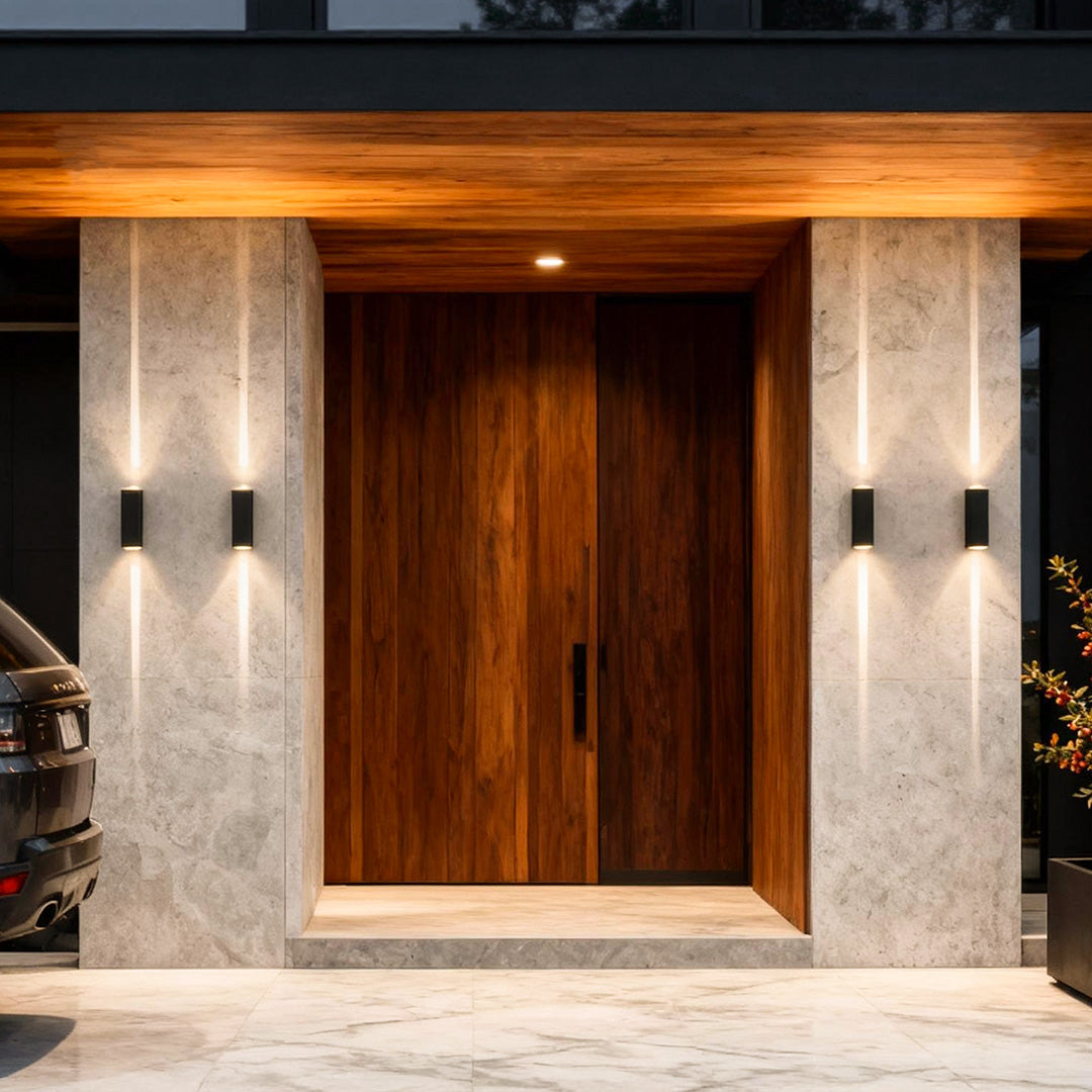 Narrow beam wall sconce installed beside a wooden front door, delivering elegant and symmetrical entrance lighting.