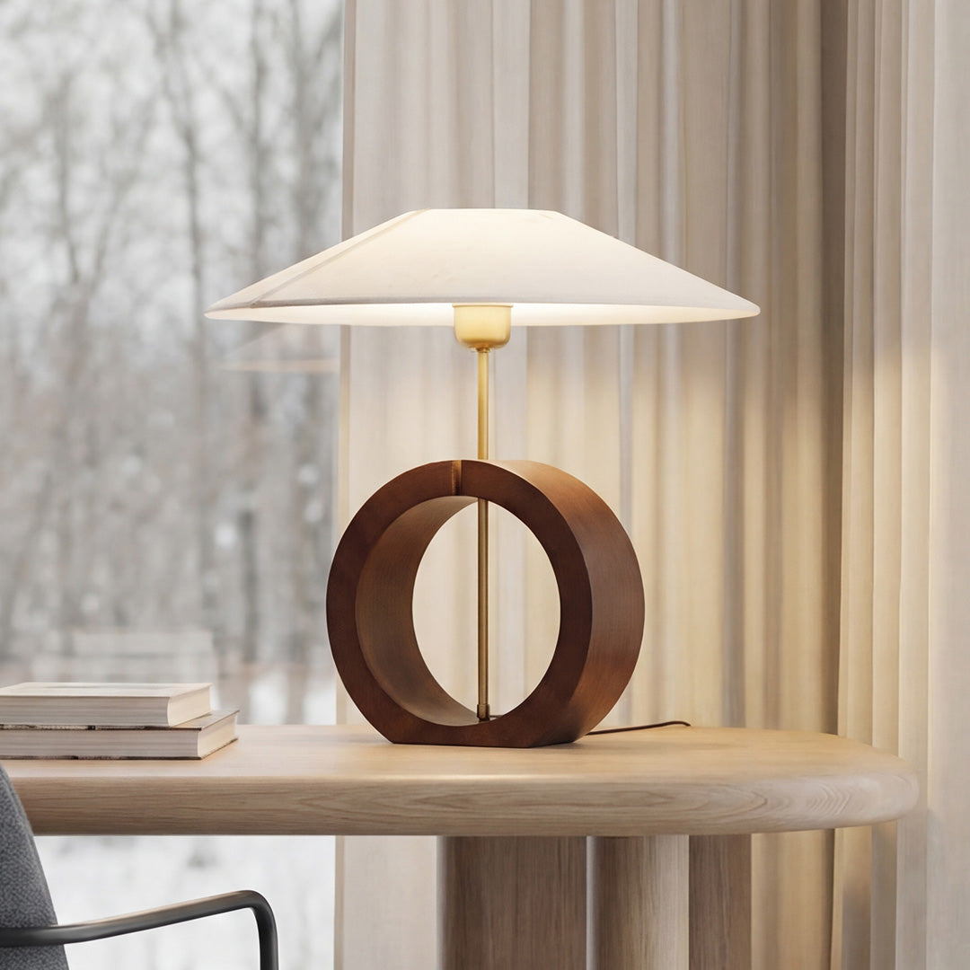 Unique natural wood table lamp with a circular wood base and wide white fabric shade on a desk.