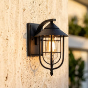 Nautical wall sconce mounted on a textured exterior wall, featuring a black cage frame and warm bulb.