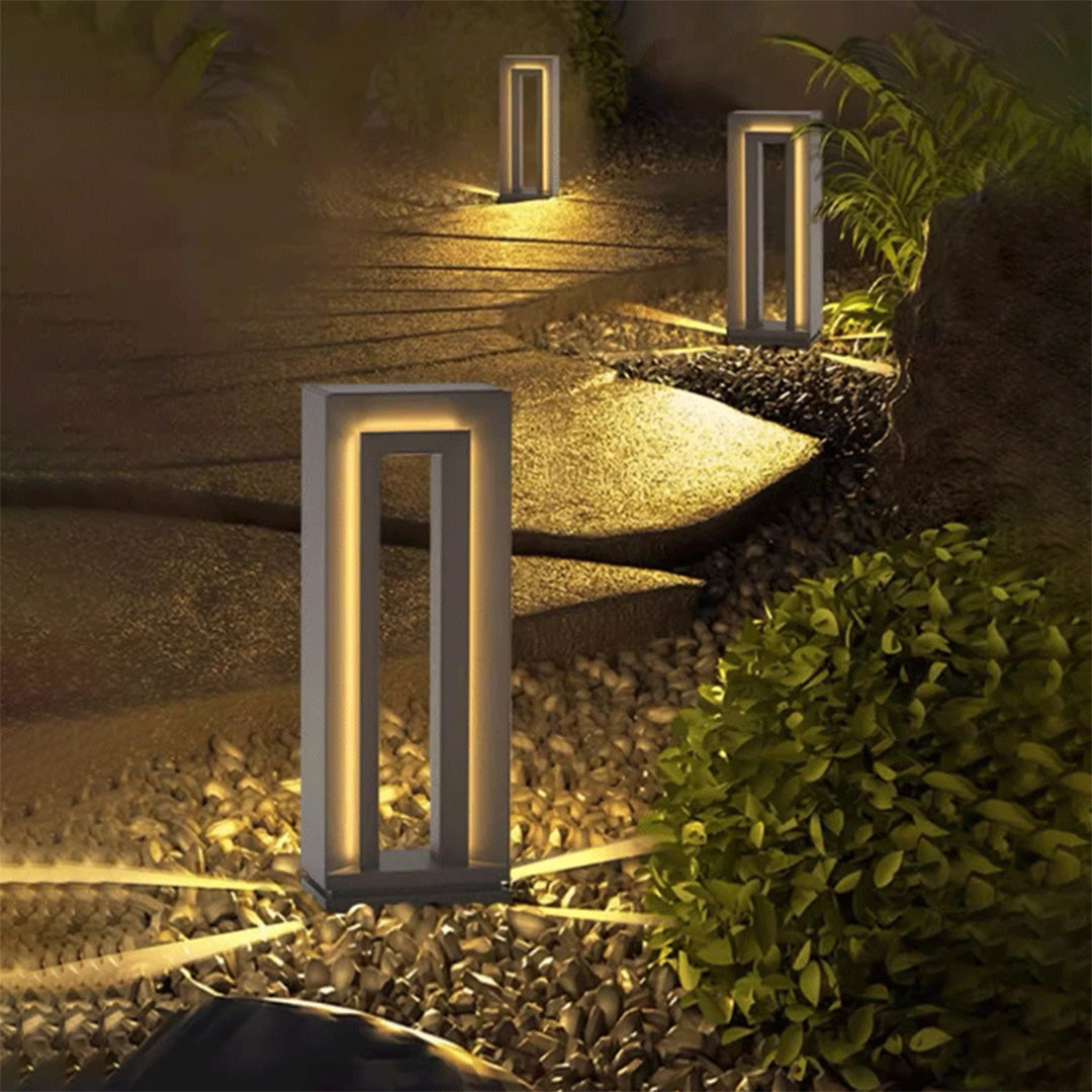 Path lined with contemporary lighted bollards LED posts producing layered night-time landscape lighting.