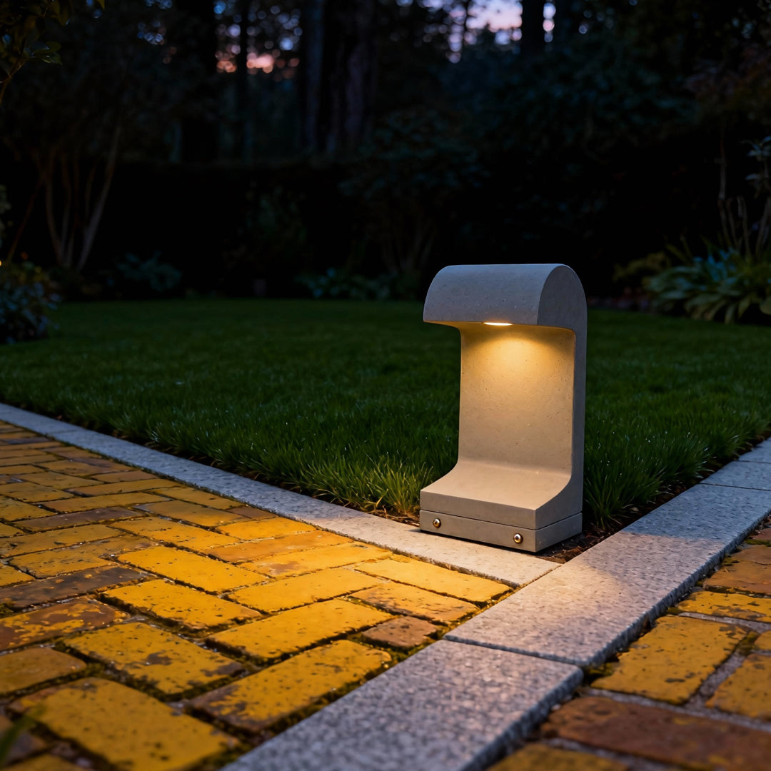 Nighttime landscape led lighting creating a soft glow along a textured garden path using a modern curved-top bollard fixture.