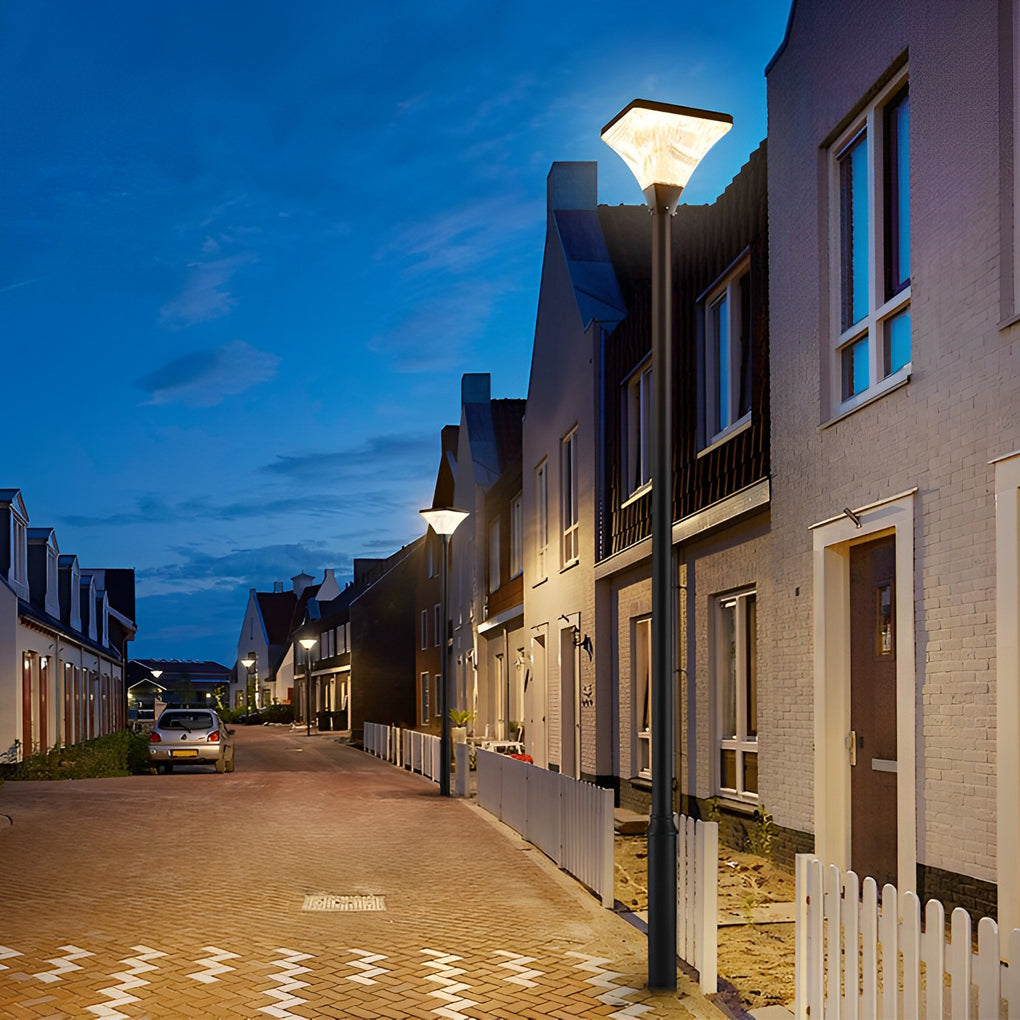 Night street lighting highlighting a narrow residential road with townhouses and fences.