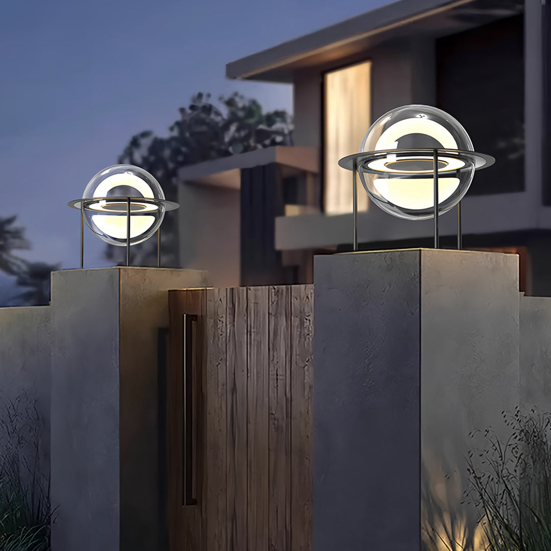 Night view of circular main gate pillar light design installed on residential gate columns with soft warm lighting.