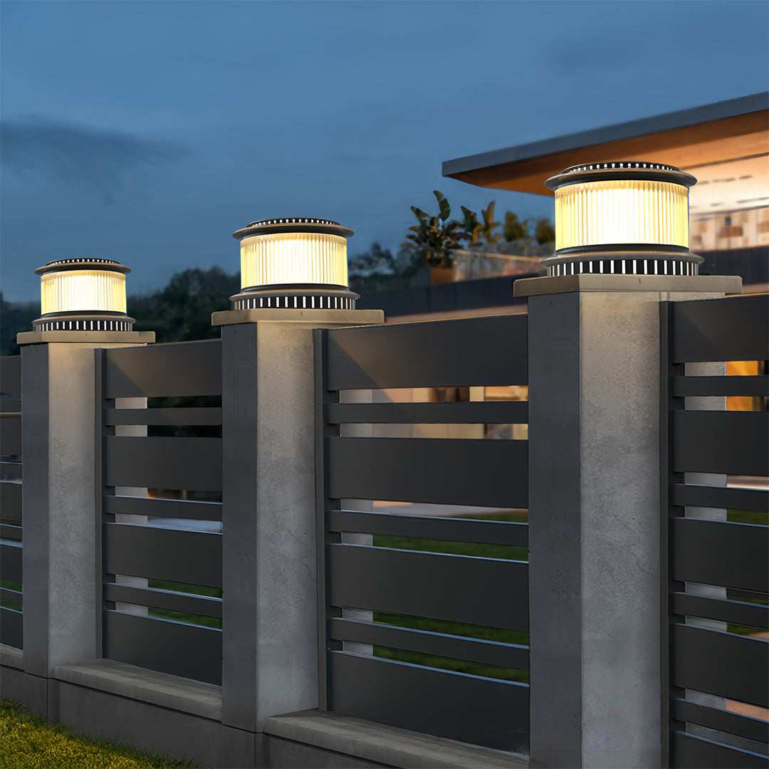 Night view of stainless steel pillar lights at the gate entrance, illuminating the surroundings with a warm glow.
