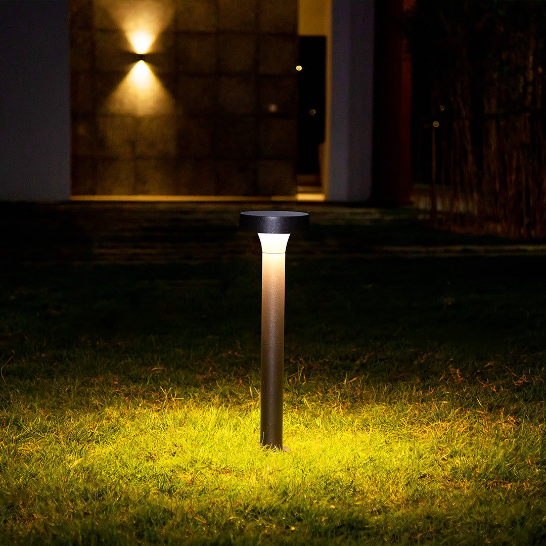 Nighttime garden scene with bollard lighting creating dramatic pools of light on grass