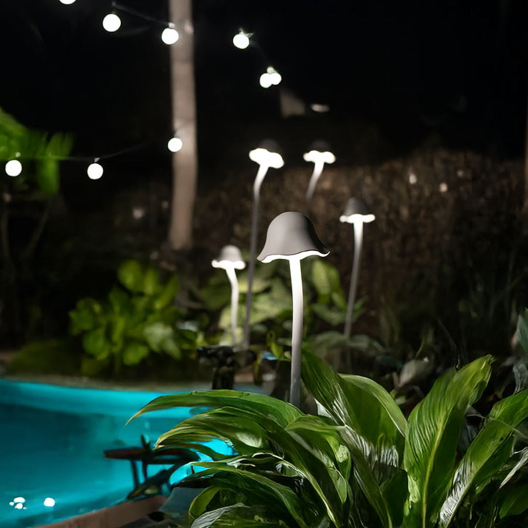 Nighttime outdoor landscape light display with multiple fixtures creating magical ambiance around water feature