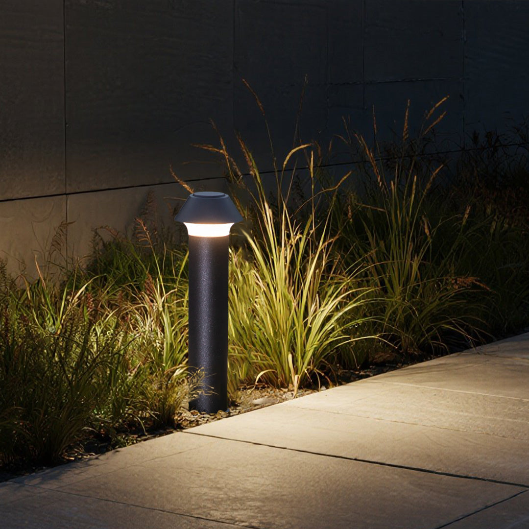 Nighttime garden scene featuring pagoda bollard lighting among ornamental grasses and pathway