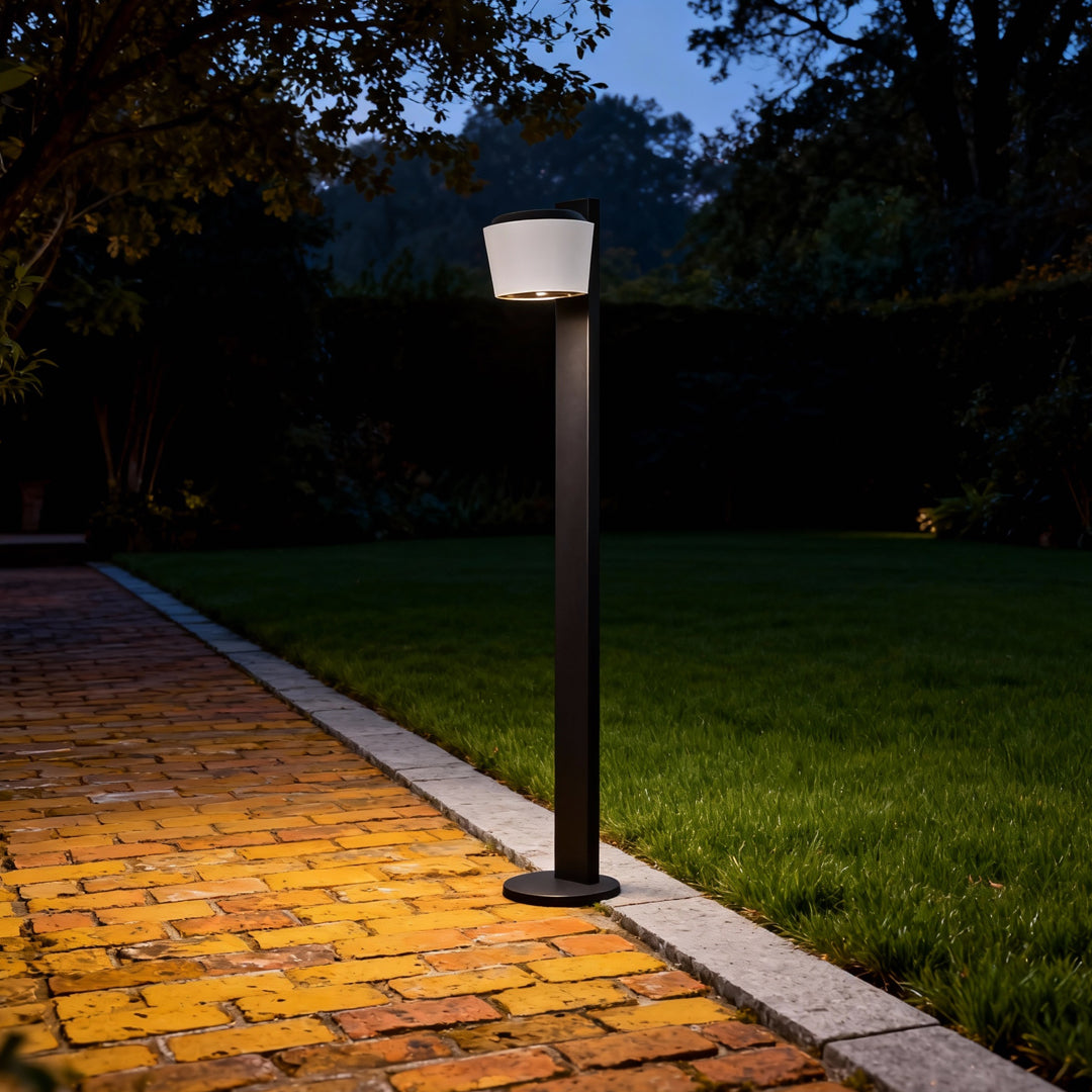 Single garden lights path fixture glowing along a nighttime walkway with decorative gravel edging.