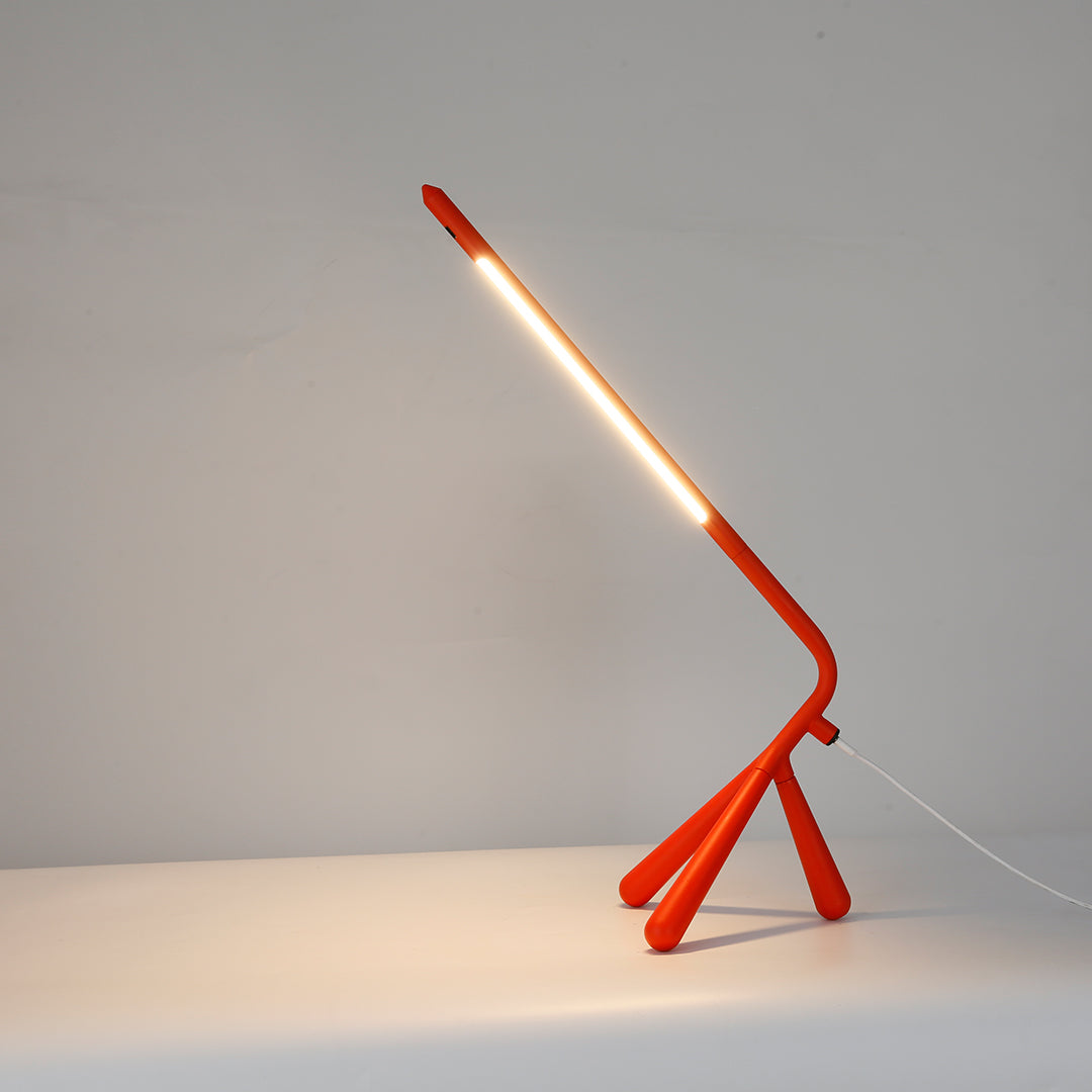 Stylish three legged table lamp with orange base complementing cozy bedroom reading nook setup