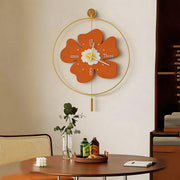 Orange flower shaped wall clock with light featuring a gold metal circular frame in a dining room.