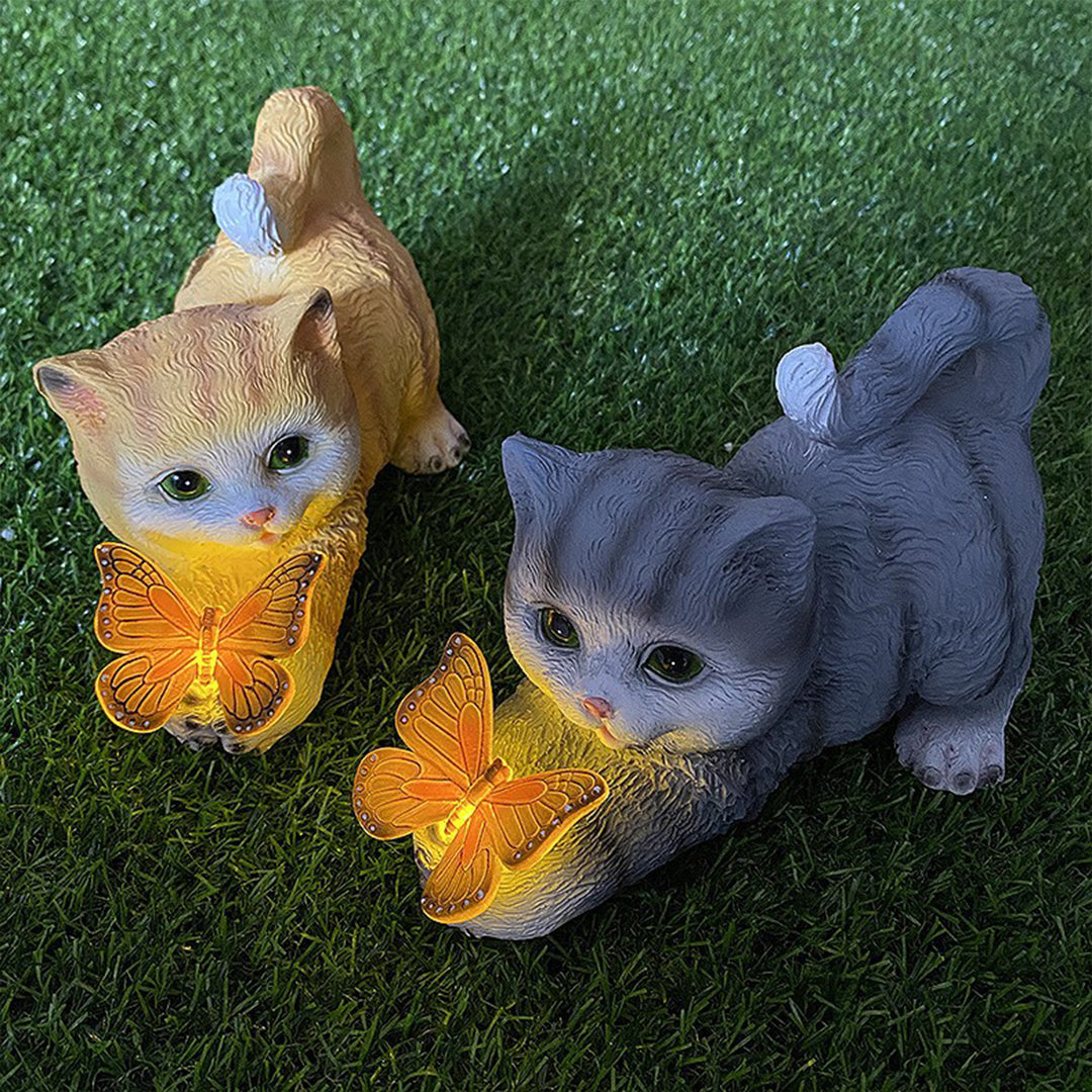 Orange and gray kitten garden ornaments with glowing butterflies on artificial grass