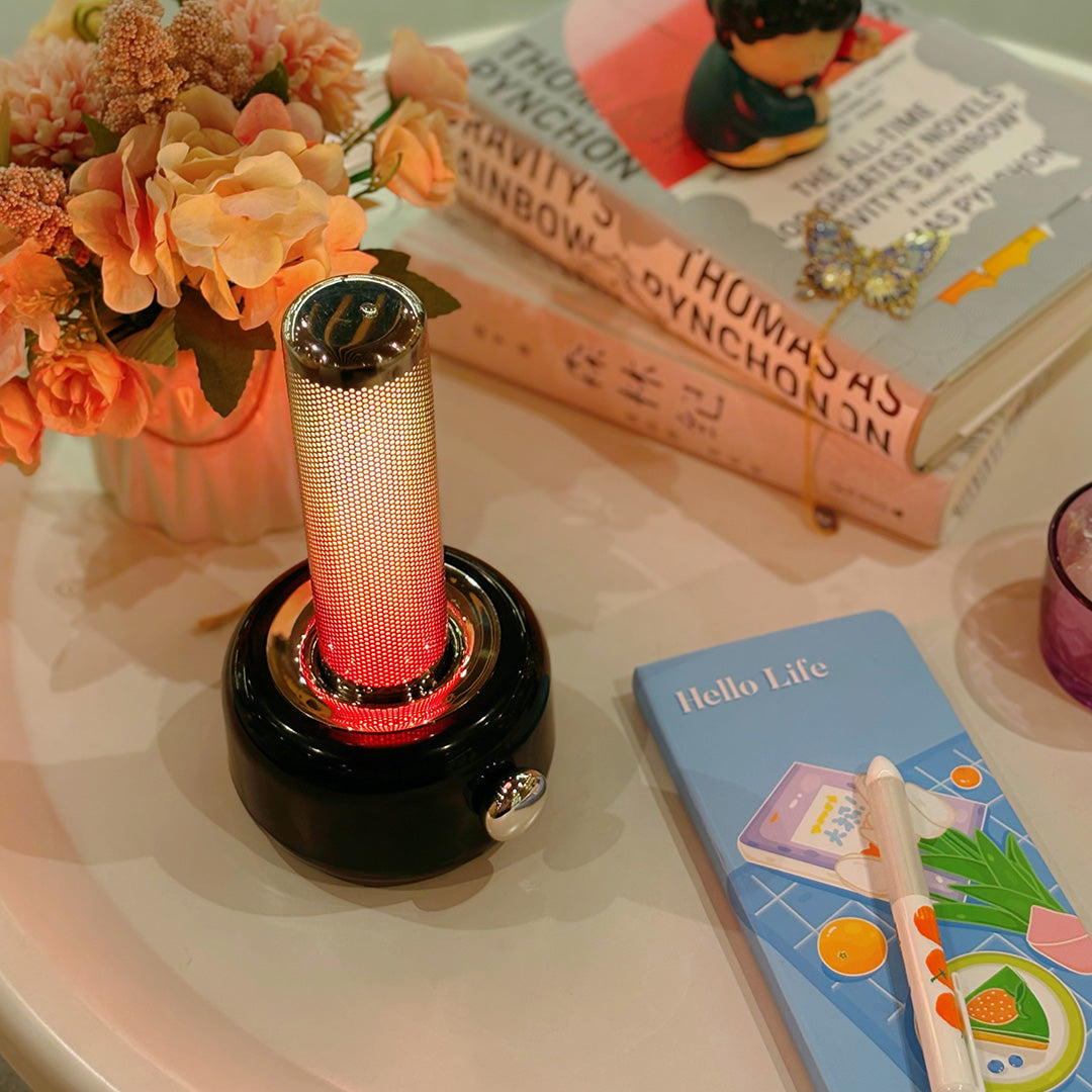 Orange industrial metal USB rechargeable table lamp illuminated on workspace with books