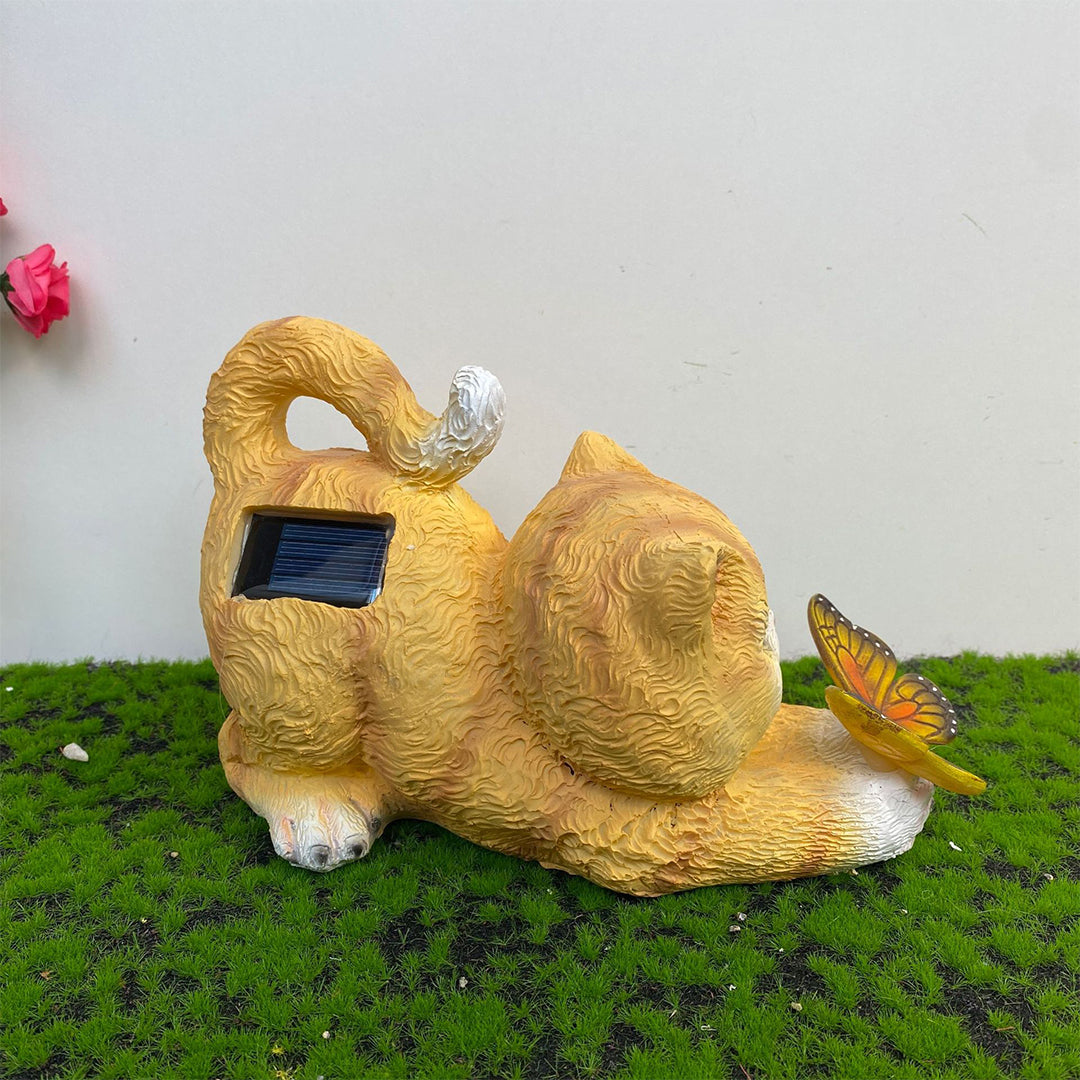 Orange tabby kitten figurine with solar-powered butterfly light on moss surface