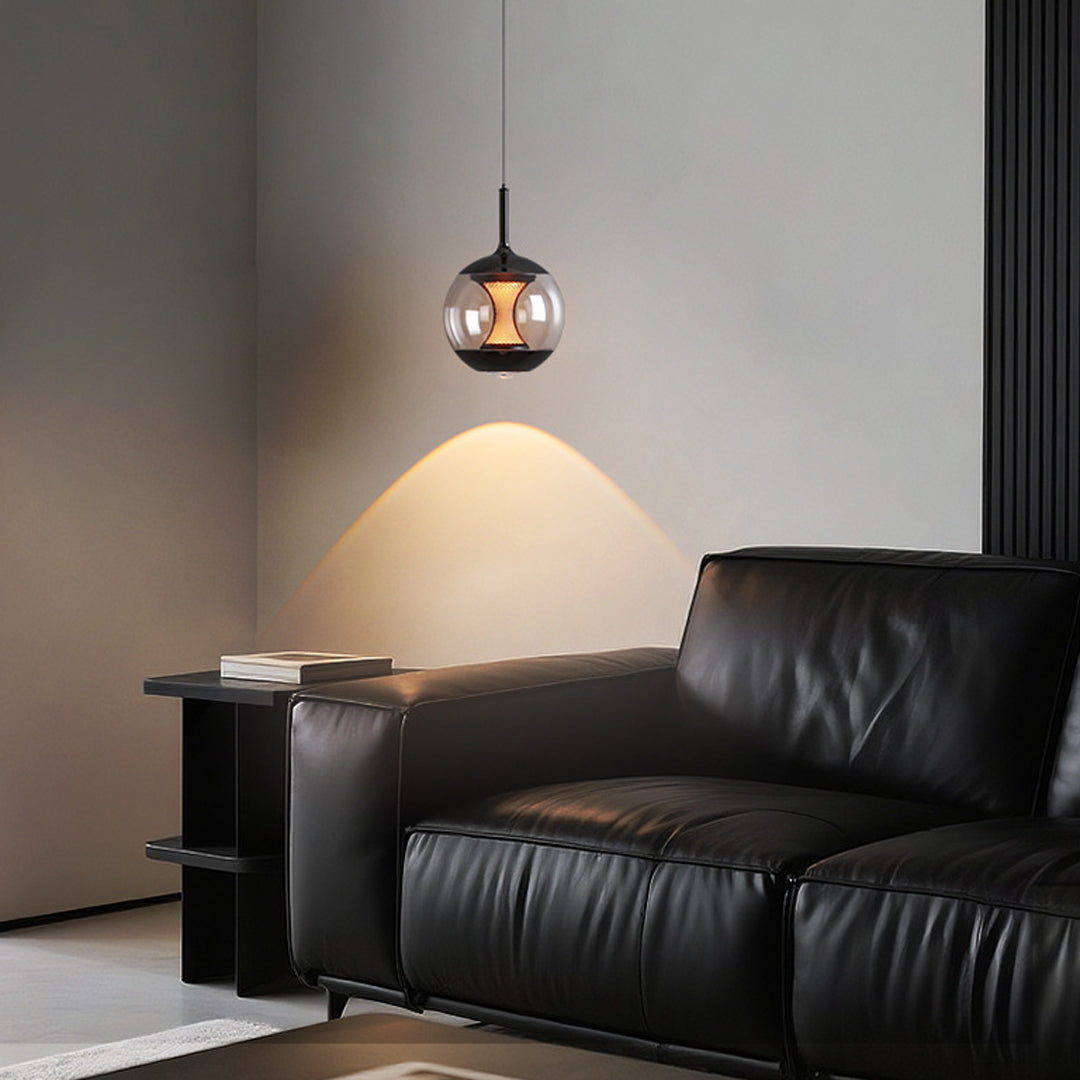 Orb pendant light illuminating modern living room corner beside black leather sofa with warm downlight effect