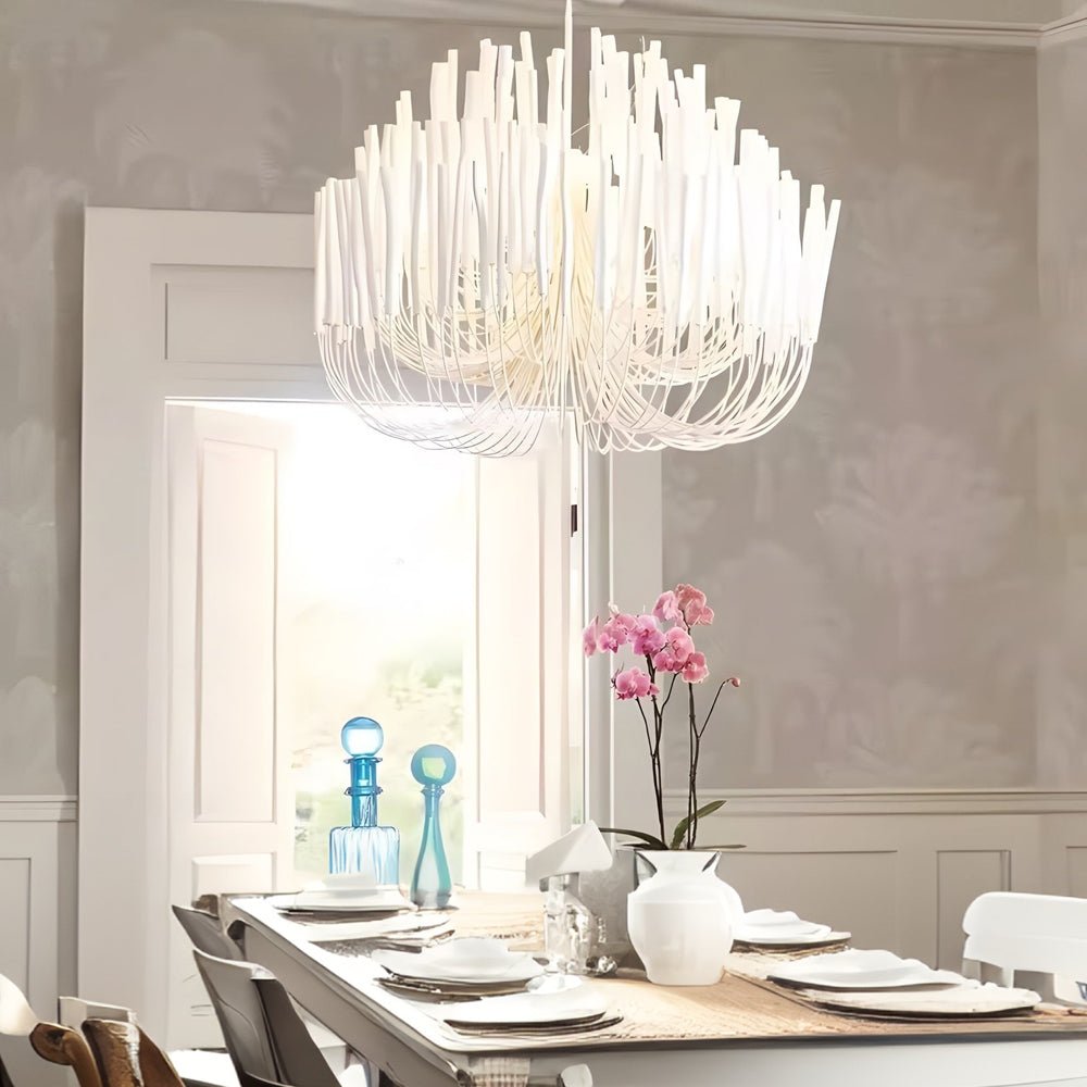 Organic stick chandelier illuminating a dining table, creating a warm and inviting atmosphere in a contemporary space.
