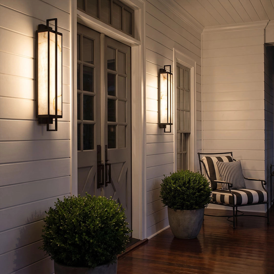 Outdoor alabaster wall sconces flanking a white porch door with warm ambient lighting.