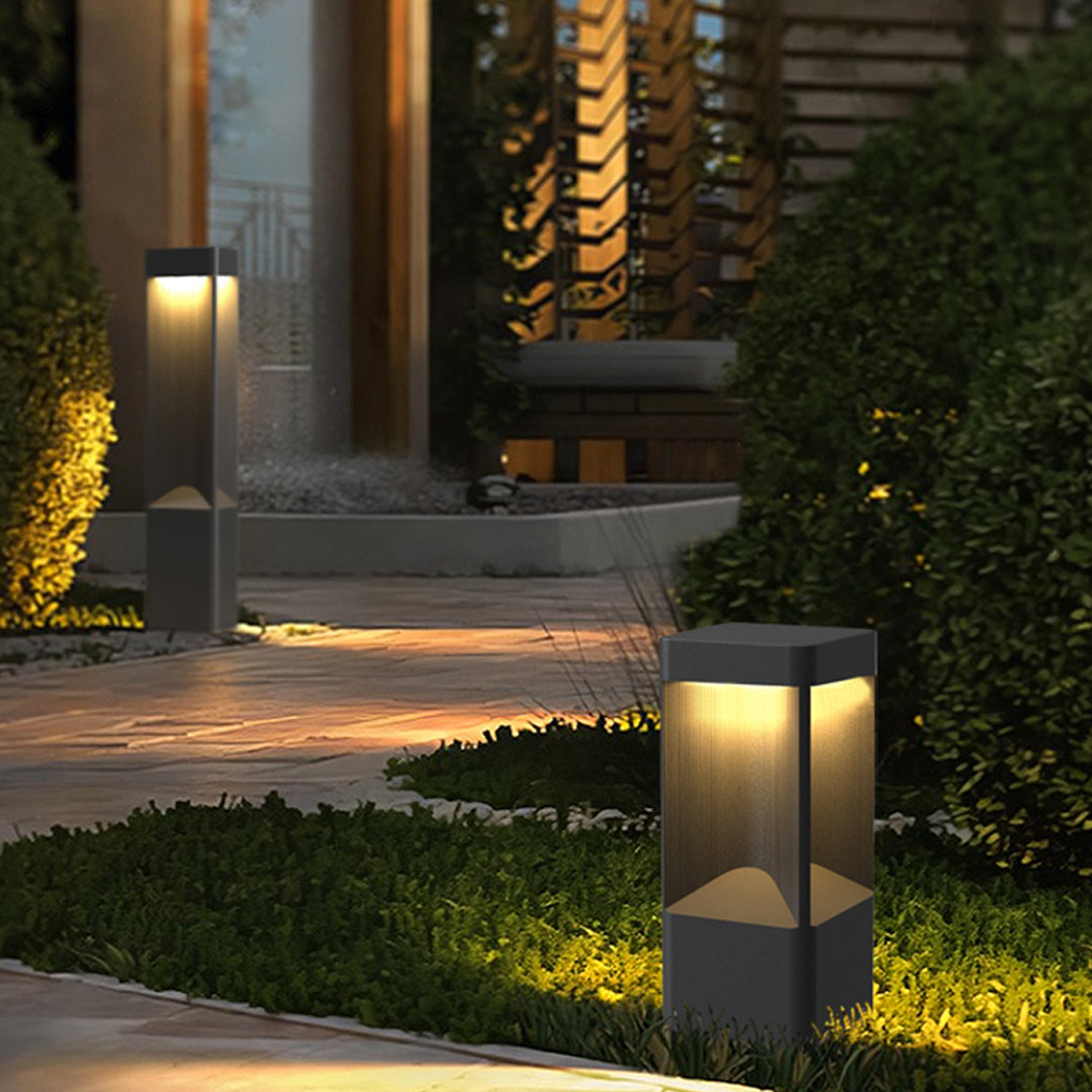 Outdoor black bollard lighting near the garden fountain area with soft warm led light at dusk.
