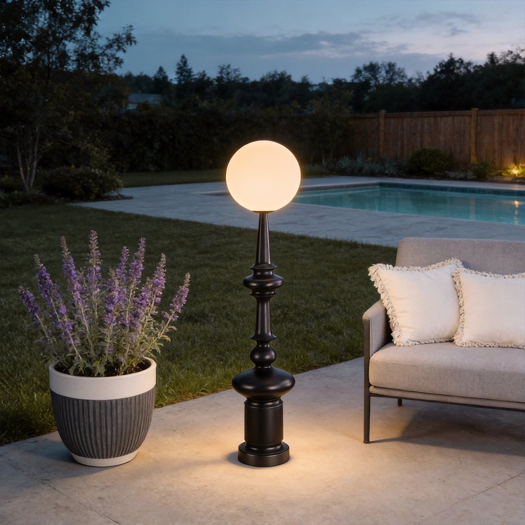 Outdoor black floor lamps with a contemporary design, providing warm illumination near a planter.
